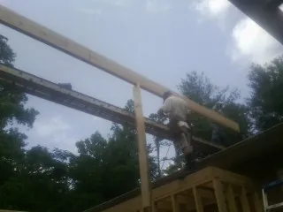 Carpenter setting a ridge beam over a new addition frame in Sterling